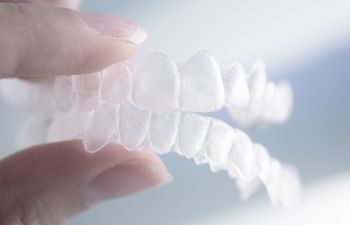a person holding a set of clear aligners with their fingers