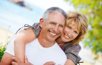 Happy cuddling mature couple with perfect smiles.