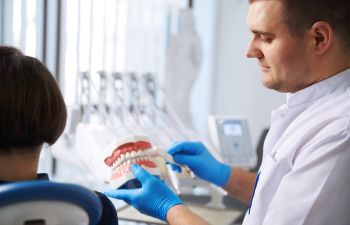 a dentist with a dental model educating patient on how to take care of dentures