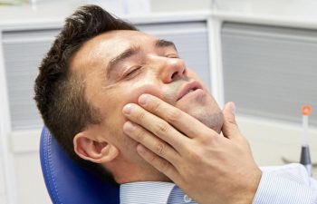 Man with severe dental pain in a dental chair waiting for the dentist.