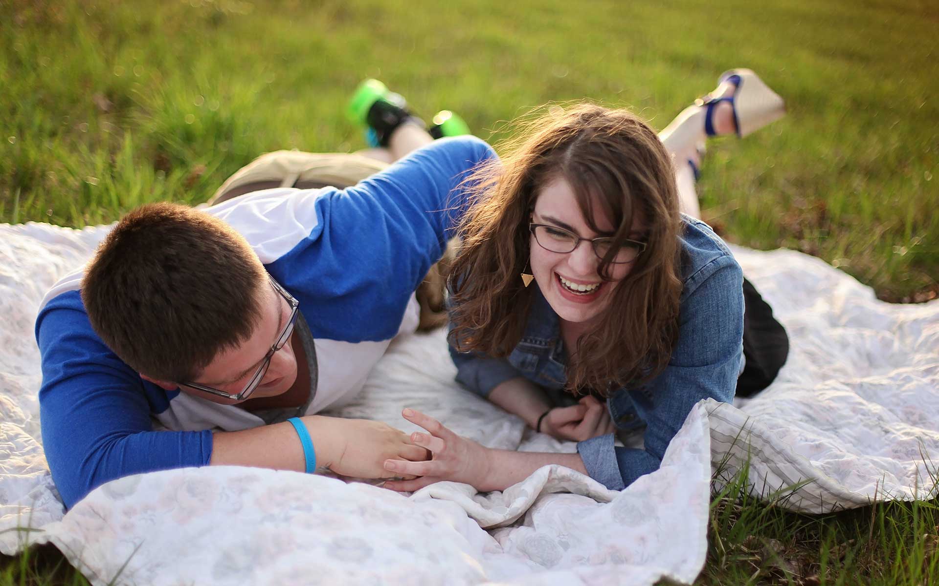 a happy smiling teenage girl with her boyfriend picknicking in a park
