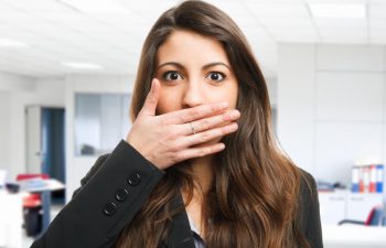 Young confused woman covering her mouth due to bad breath.