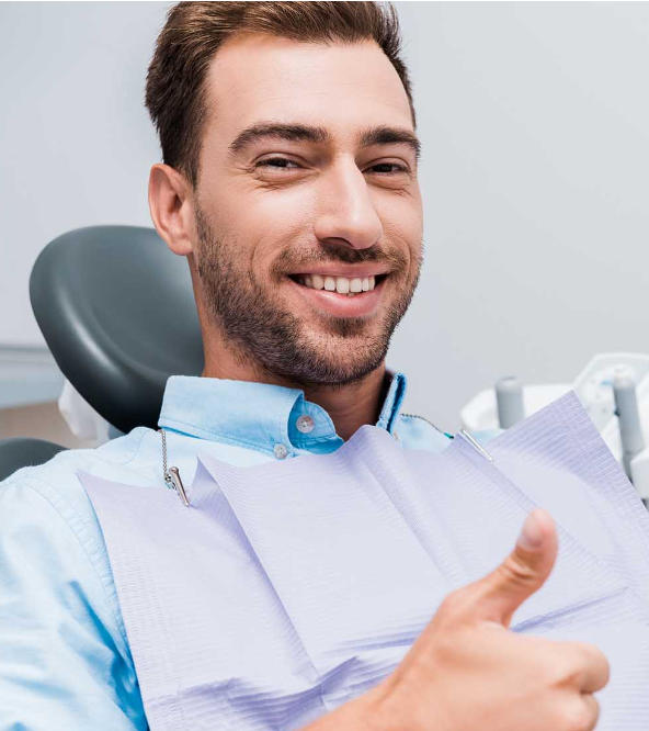 Satisfied middle-aged man in a dental chair showing his thumb up.