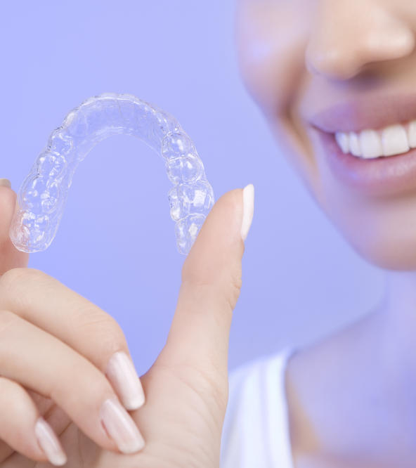 Woman presenting an Invisalign aligner.