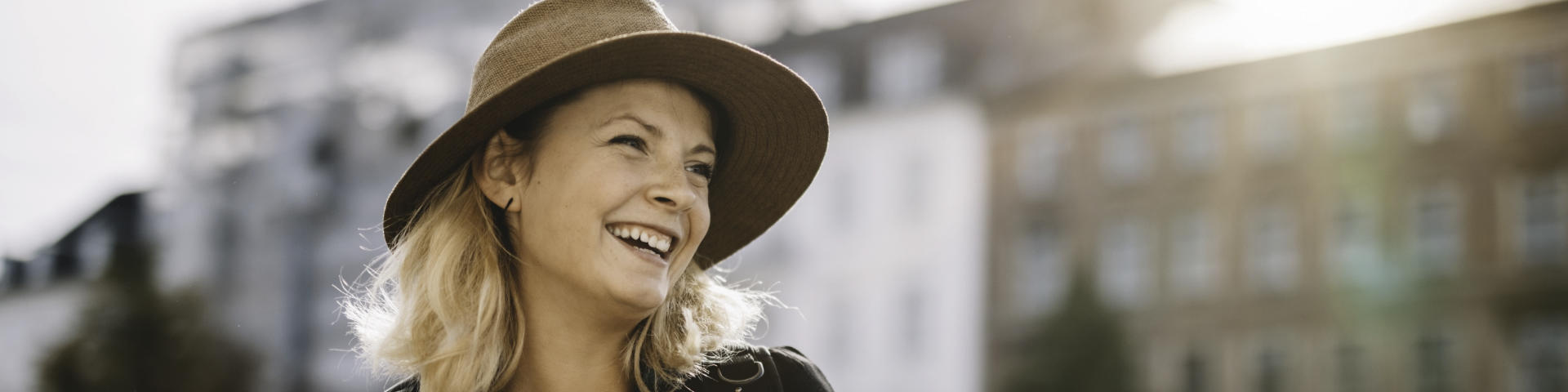 Cheerful broadly smiling woman wearing a hat.