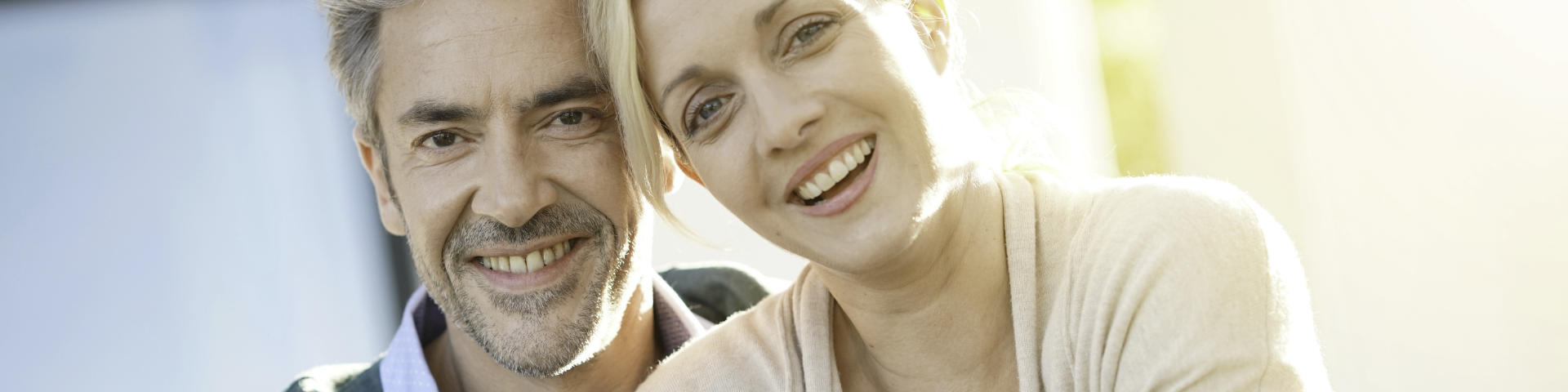 Happy middle-aged couple showing perfect teeth in their smiles.