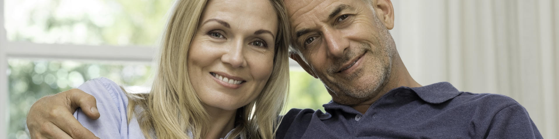 Happy middle-aged couple showing perfect teeth in their smiles.