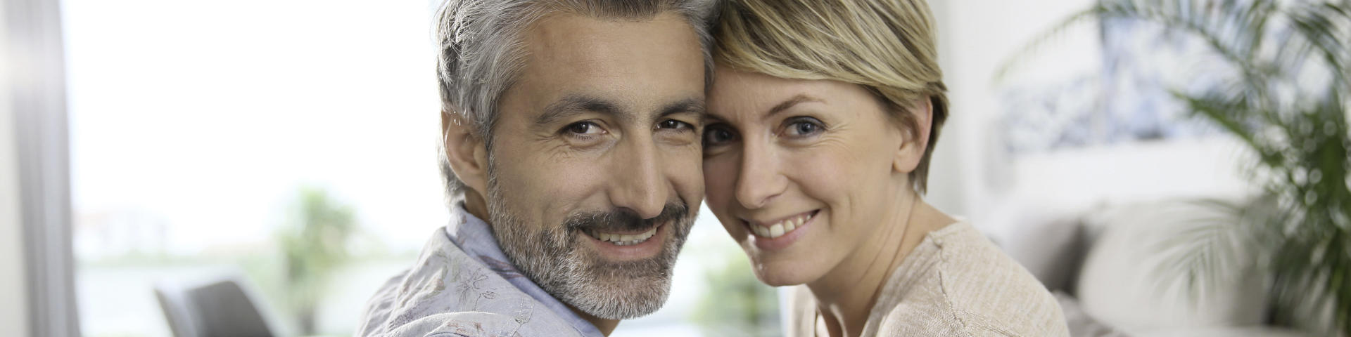 Happy middle-aged couple showing perfect teeth in their smiles.