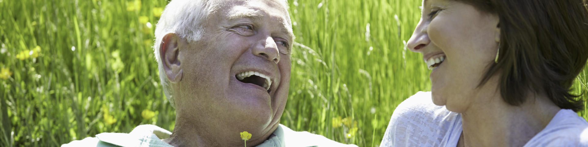 Happy laughing senior couple picnicking on the grass.