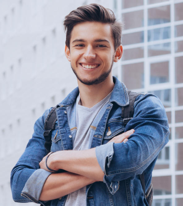 Joyful young man showing nice teeth in his smile standing in front of an office building.