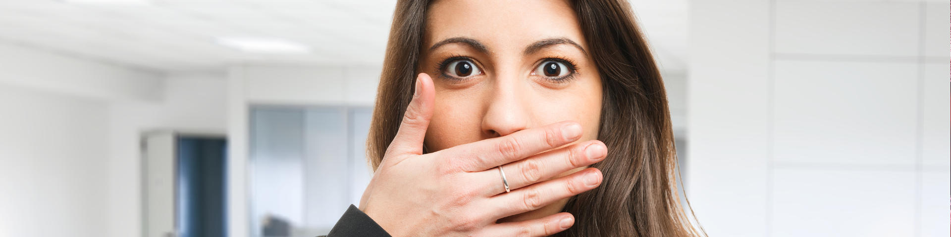 Young confused woman covering her mouth due to bad breath.