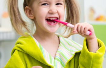 Little happy girl brushing her teeth.