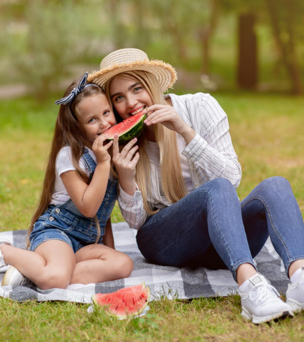 Happy mother with her daughter eating water melon at the picnic.