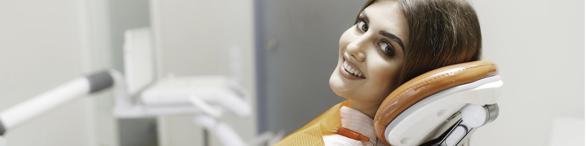 Satisfied young woman with perfect smile in a dental chair.