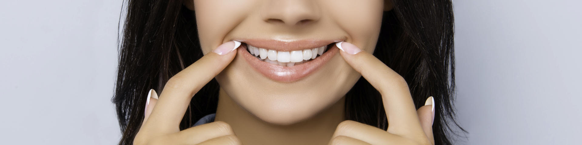 Happy woman pointing at her perfect teeth.