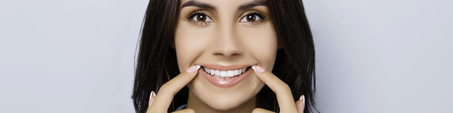 Happy woman pointing at her whitened teeth.