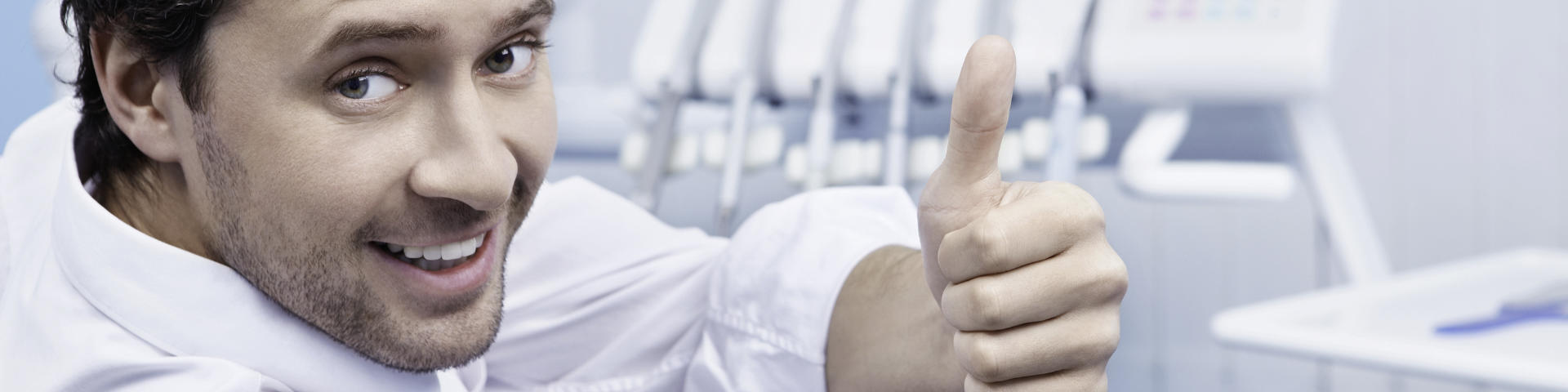 Satisfied middle-aged man in a dental chair showing his thumb up.