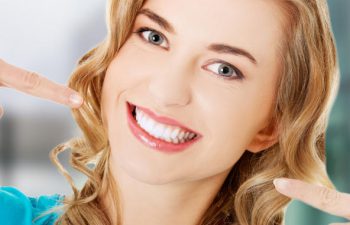 satisfied woman points at her perfect smile
