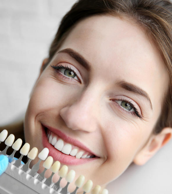 Dentist matching veneers color with woman's natural teeth color.