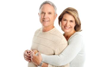 A smiling girl holdin a dental model with traditional braces in one hand and a clear aligner in the other.