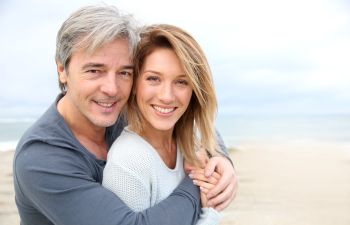 Cheerful mature couple with perfect smiles enjoying a day on a beach.