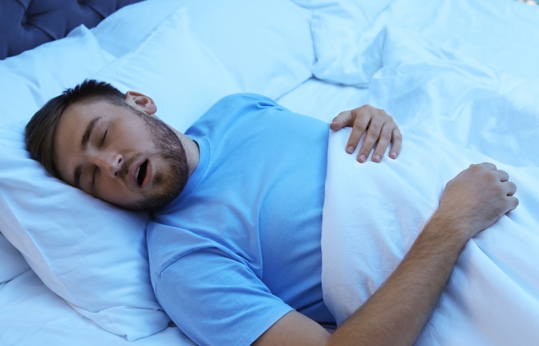 Young man snoring while sleeping in bed at night. Sleep disorder